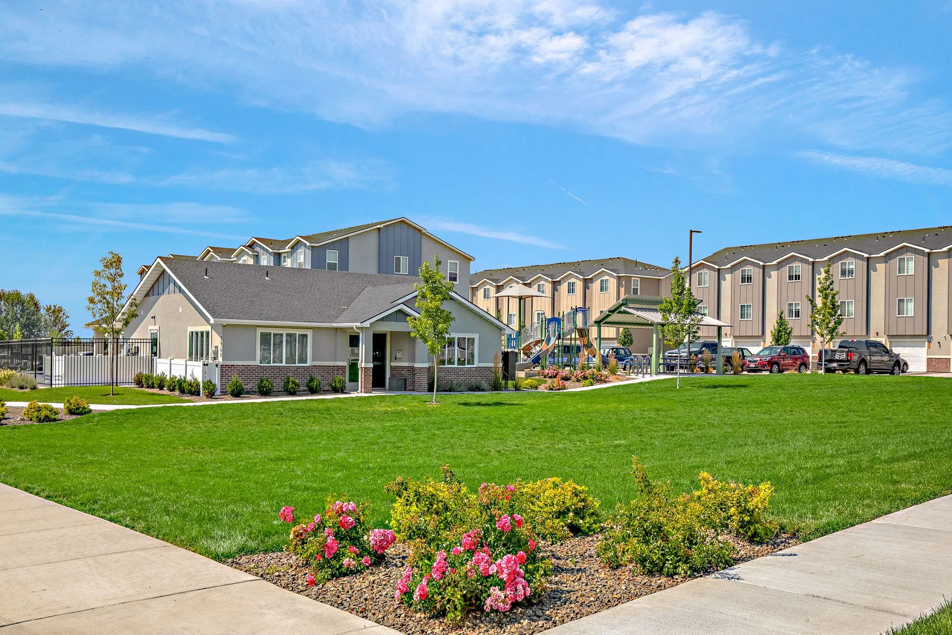 A completed multi-family residential community featuring modern apartment buildings, a clubhouse, a playground, and professional landscaping, showcasing a successful feasibility and development project by ILCC.