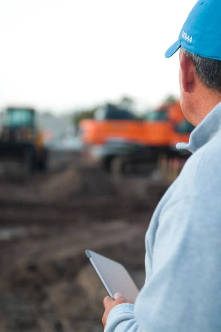 A land development consultant looking at an active construction site with excavators, illustrating the importance of identifying project risks early in Florida.